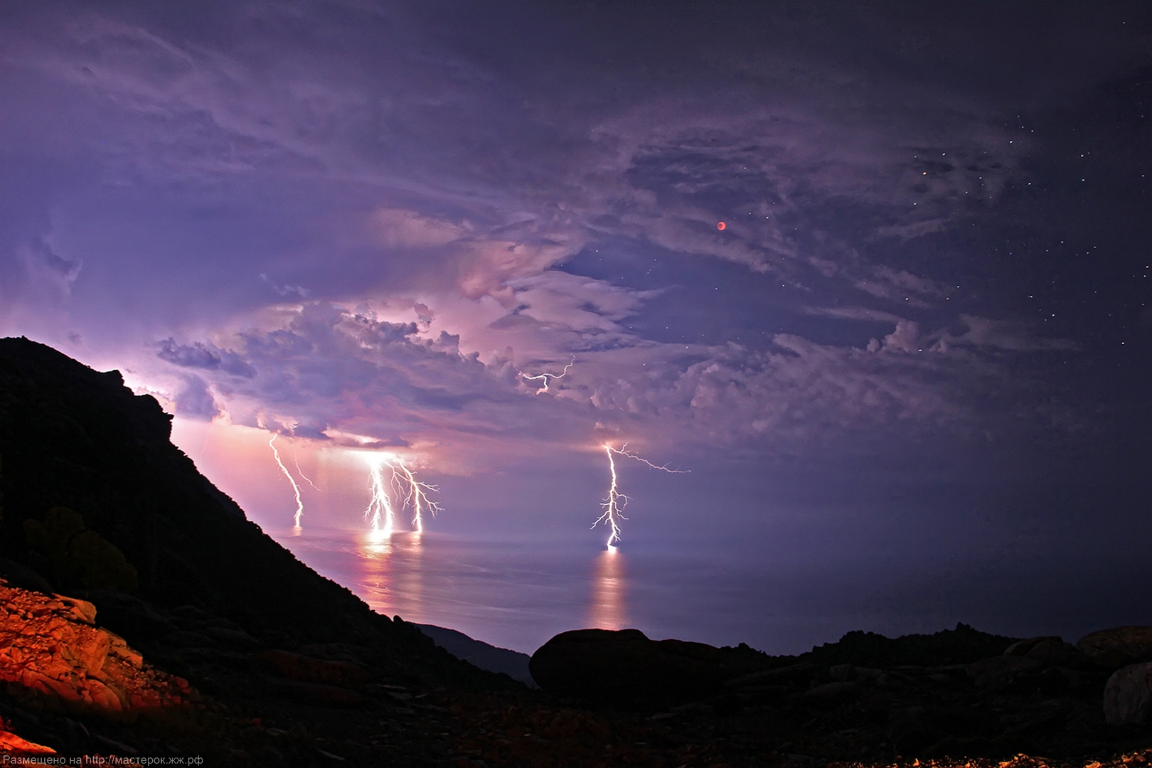 Two separate lightning bolts converge over Table Mountain in Cape Town, South Africa, with an amazing display of natural electricity.