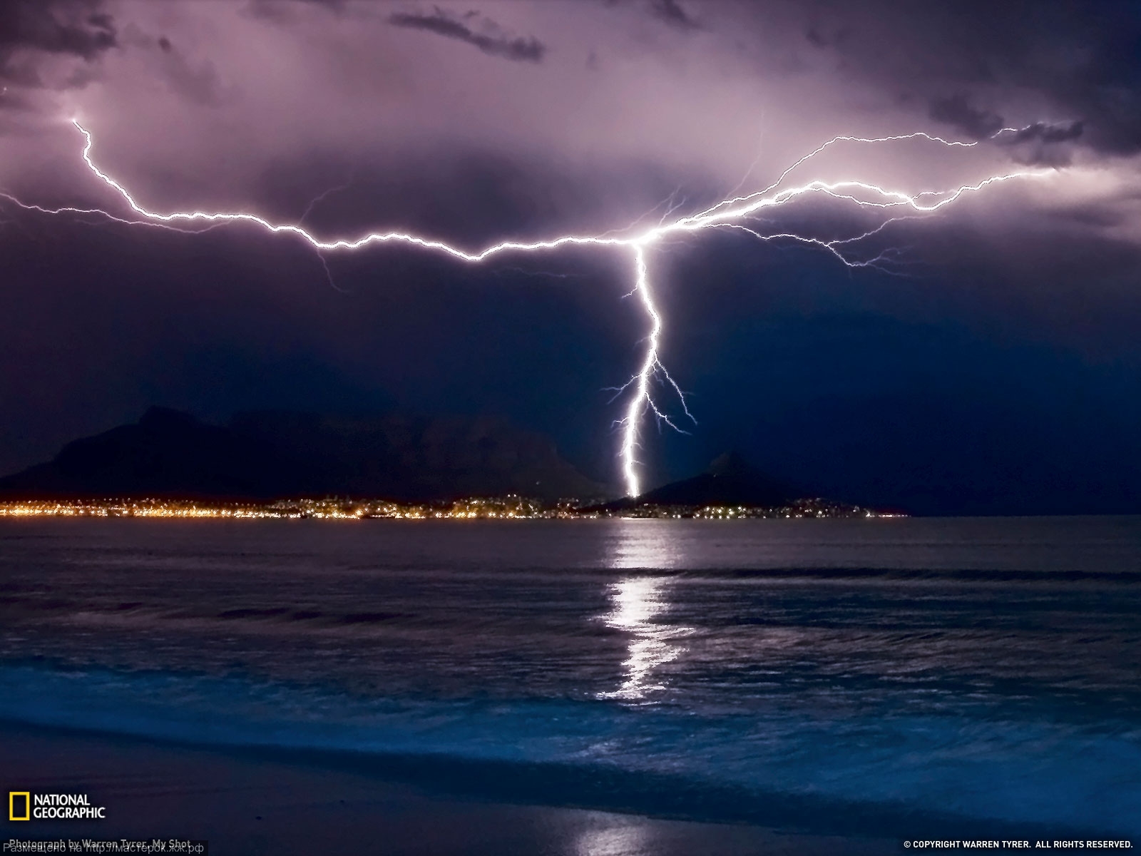 Two separate lightning bolts converge over Table Mountain in Cape Town, South Africa, with an amazing display of natural electricity.