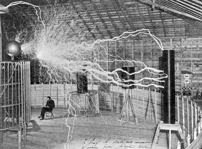 Знаменитое фото: Тесла спокойно читает бумаги под разрядами переменного тока, которые создают окружающие его установки
